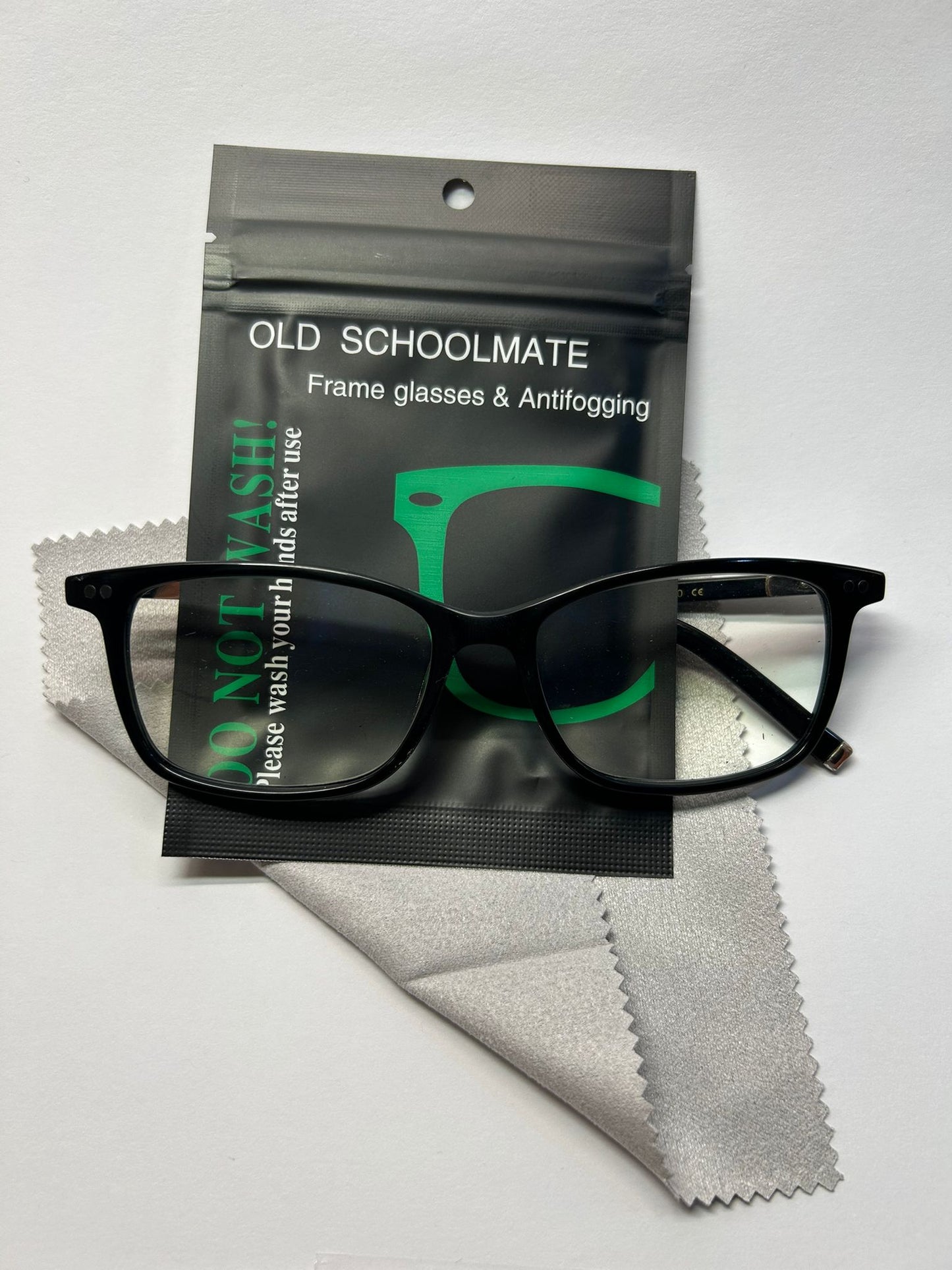 Black glasses with Old Schoolmate packaging and cleaning cloth on a white background