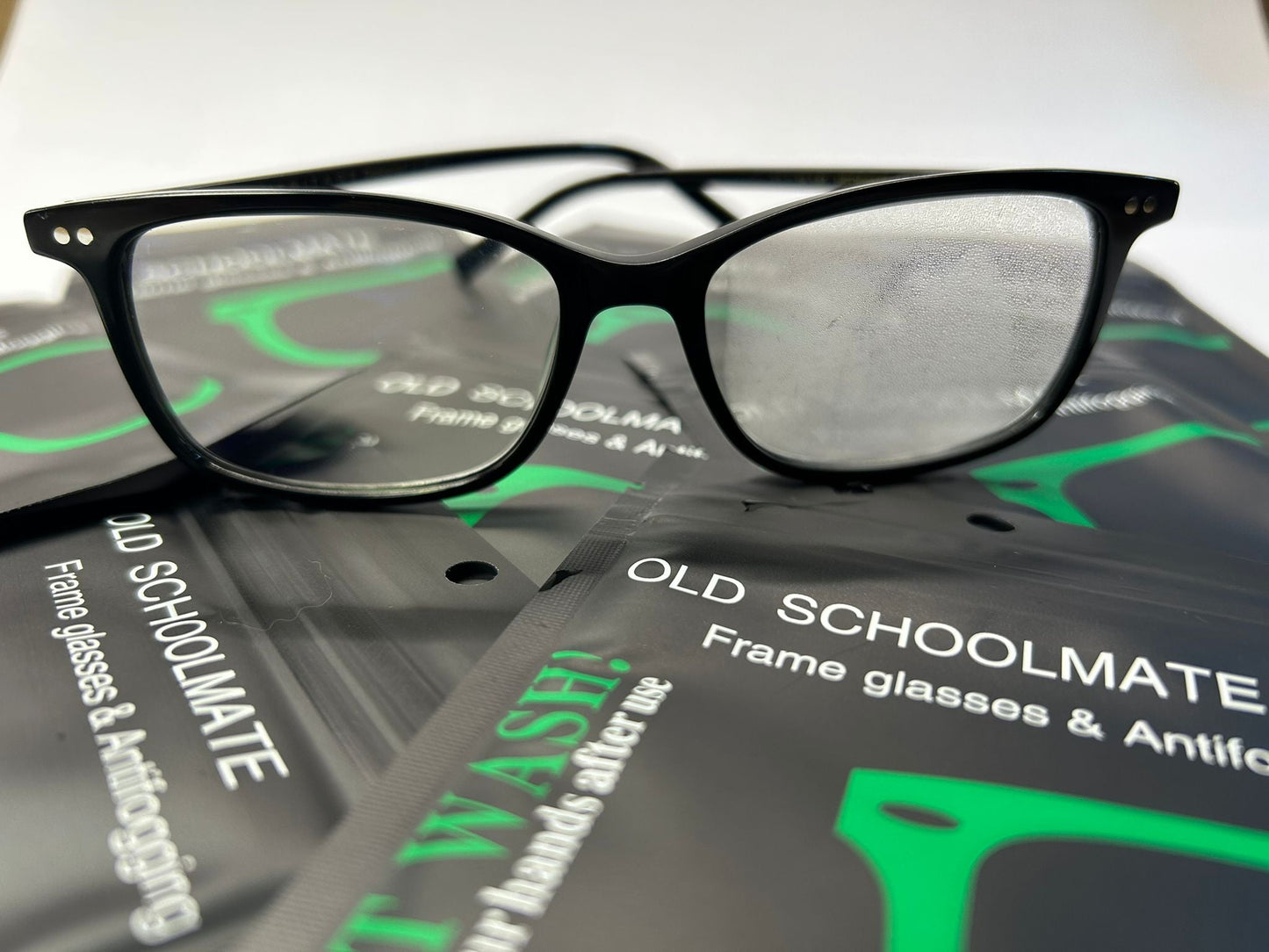 Black-framed glasses on a package of Old Schoolmate frame glasses and antifogging products.