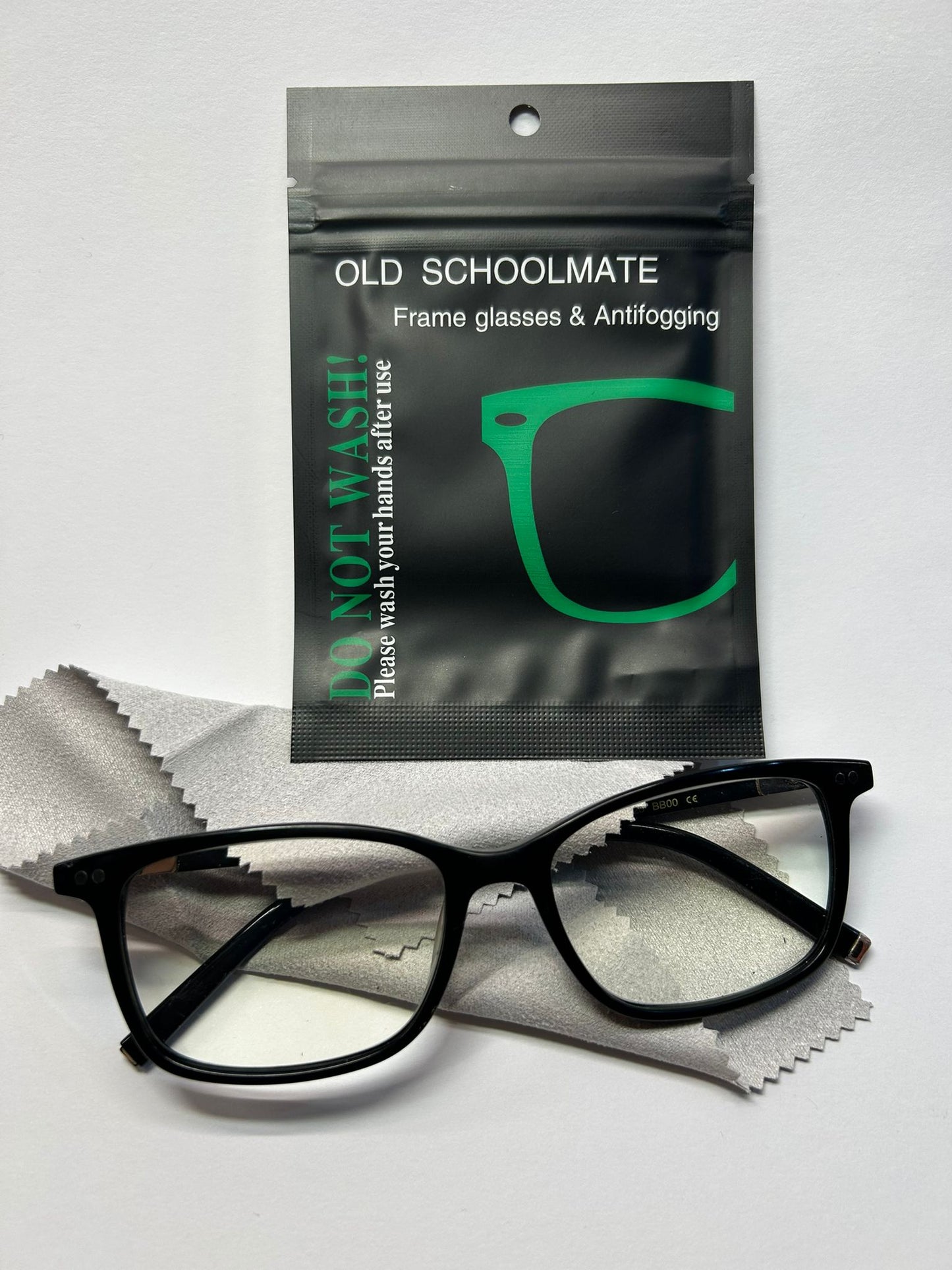Black glasses with a 'Old Schoolmate' antifogging packet on a white background