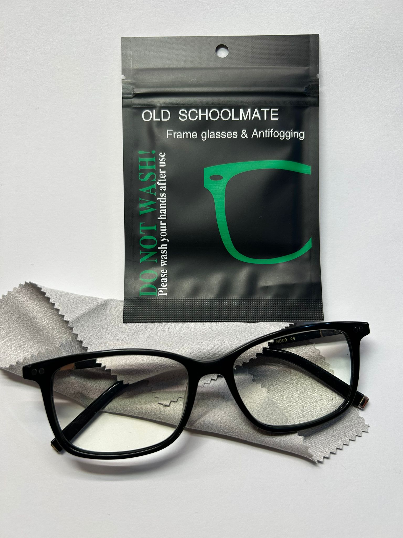 Black glasses with a 'Old Schoolmate' antifogging packet on a white background